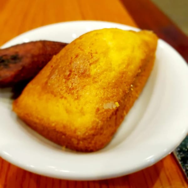 Golden cornbread and a dark brown fried plantain on a white plate at Jake's Soulfood Cafe.