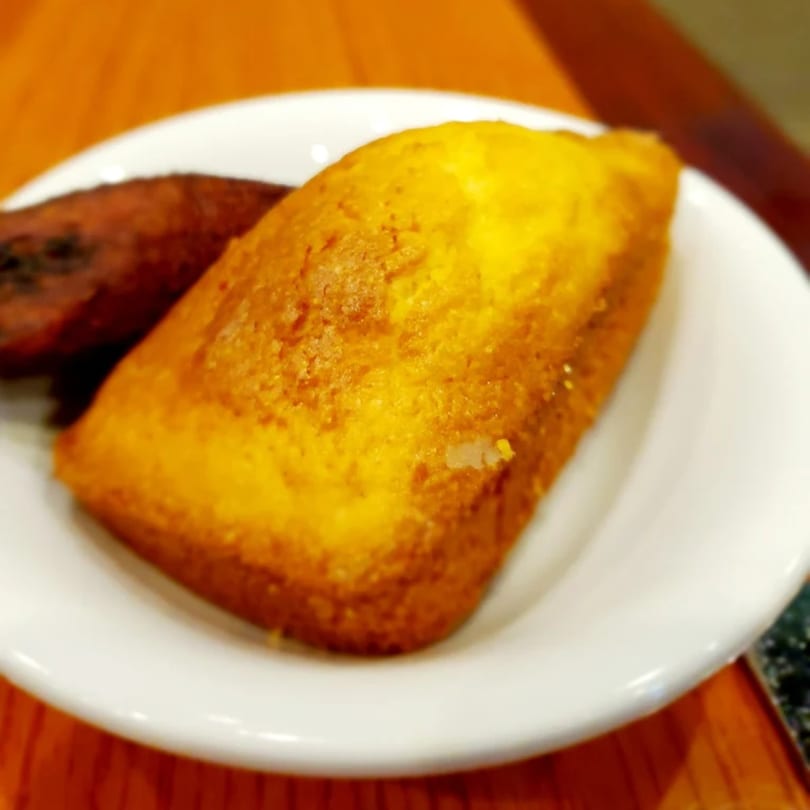 Golden cornbread and a dark brown fried plantain on a white plate at Jake's Soulfood Cafe.
